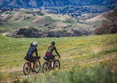 Two female friends mountain biking on single track trail.