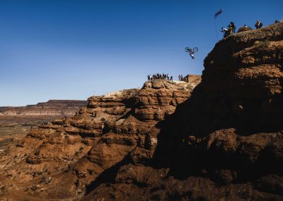 Establishing profile shot of huge front flip off cliff in red bull rampage.