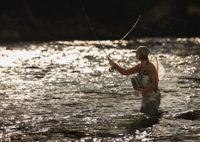 Beautiful photo of woman standingin river casting while fly fishing.