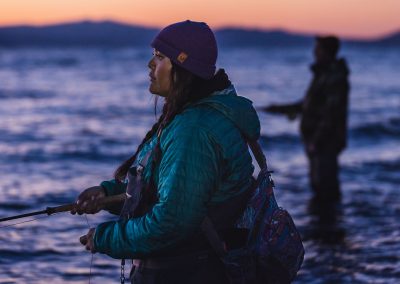 Woman fly fishing at evening with focus on water.