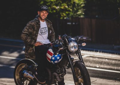 Man with sitting on street bike smiling.