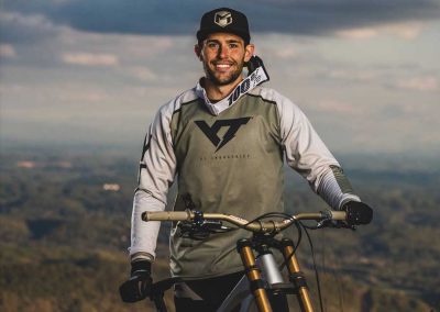 Rider standing in front of bike with sponsored gear on.