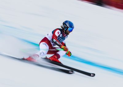 Male ski racer skiing downhill with blurred background going very fast.