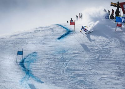 Establishing shot of male ski racer cutting a turn in hard packed snow.