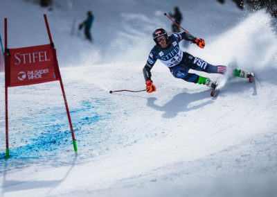 Man ski racing with USA uniform on steep downhill ski run.