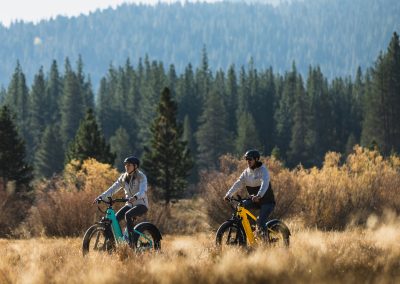 Two people riding e-bike in beautiful outdoor setting.