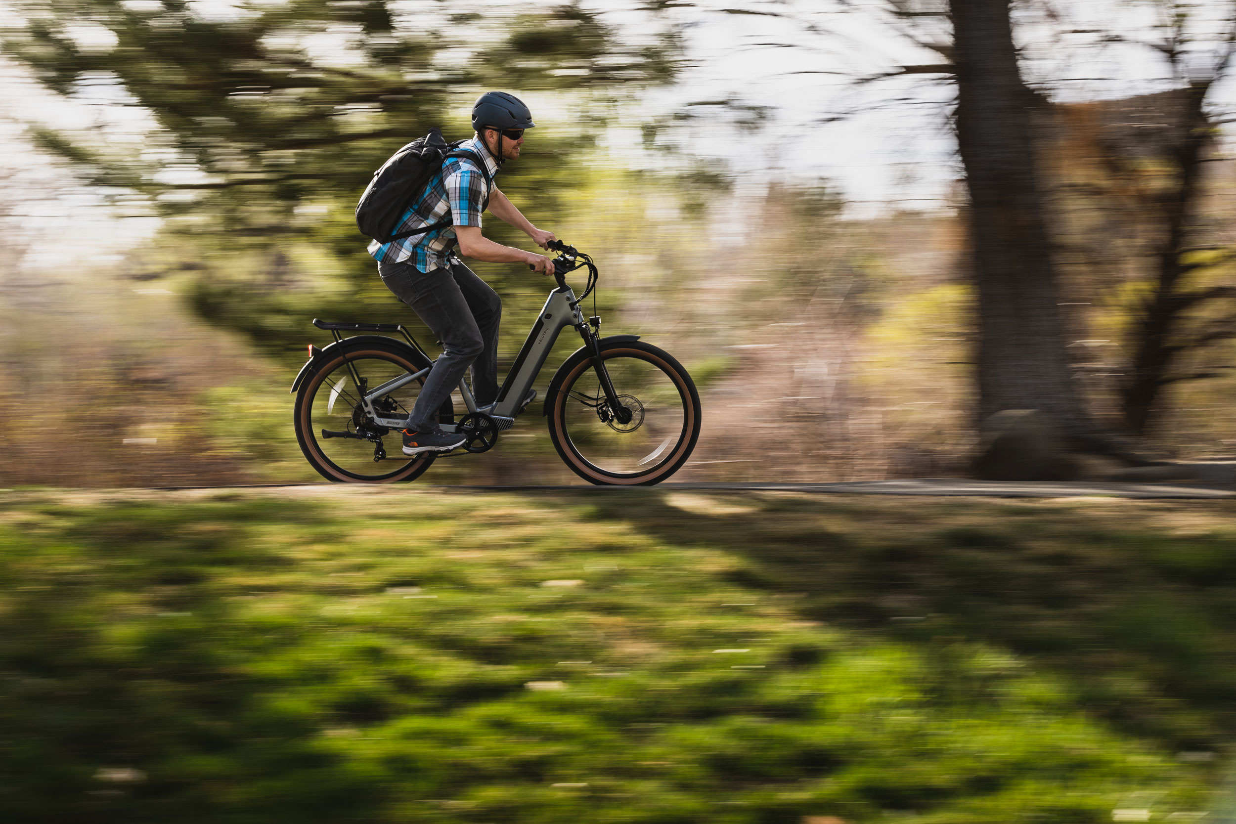 Young man riding e-bike with blurred background.